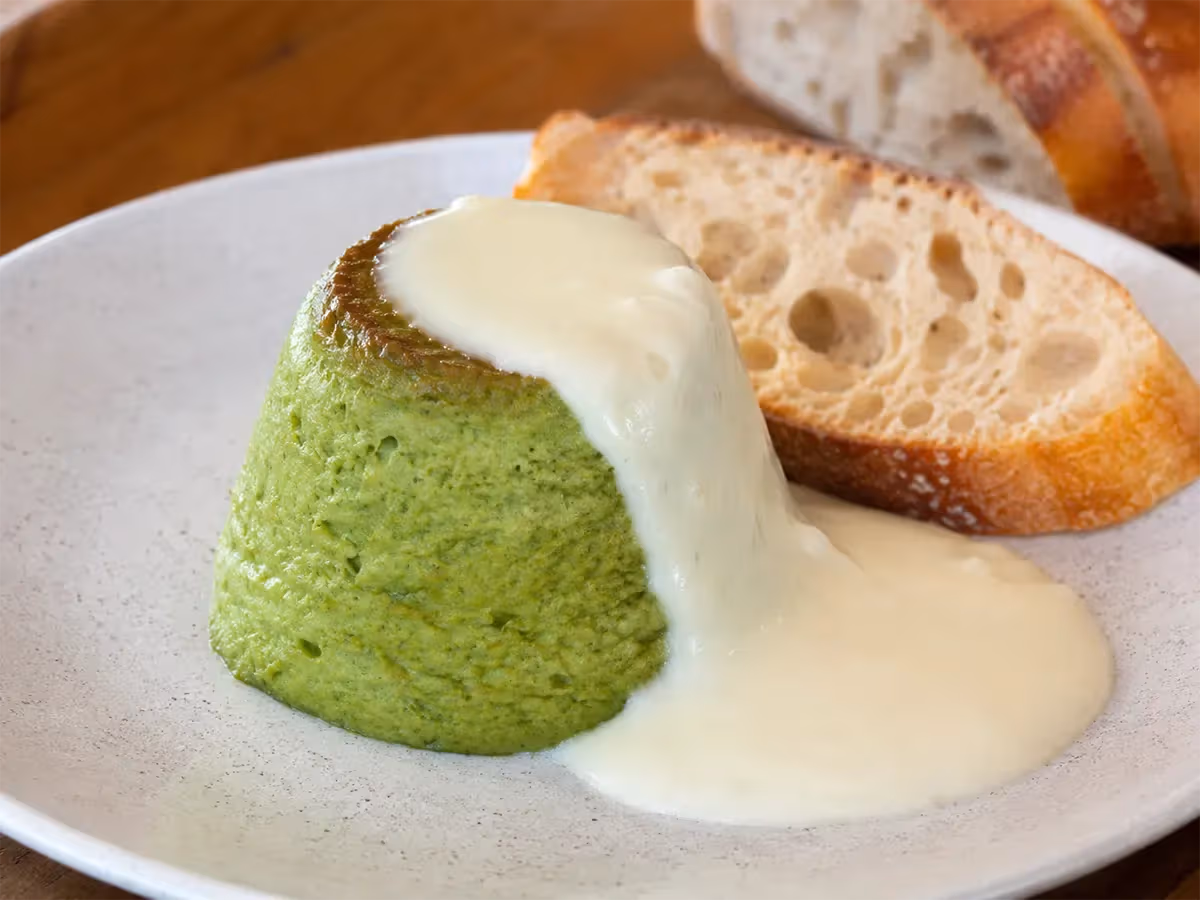 Sformatino verde di verdure coperto da salsa bianca di Fontina su piatto bianco