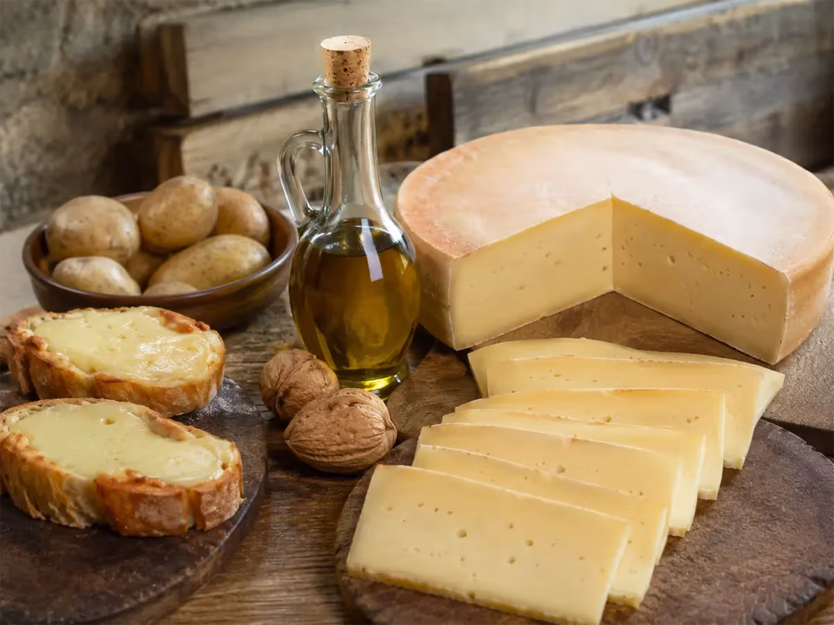 Forma di Fontina tagliata a fette sottili giallo paglierino affiancata da noci e crostini