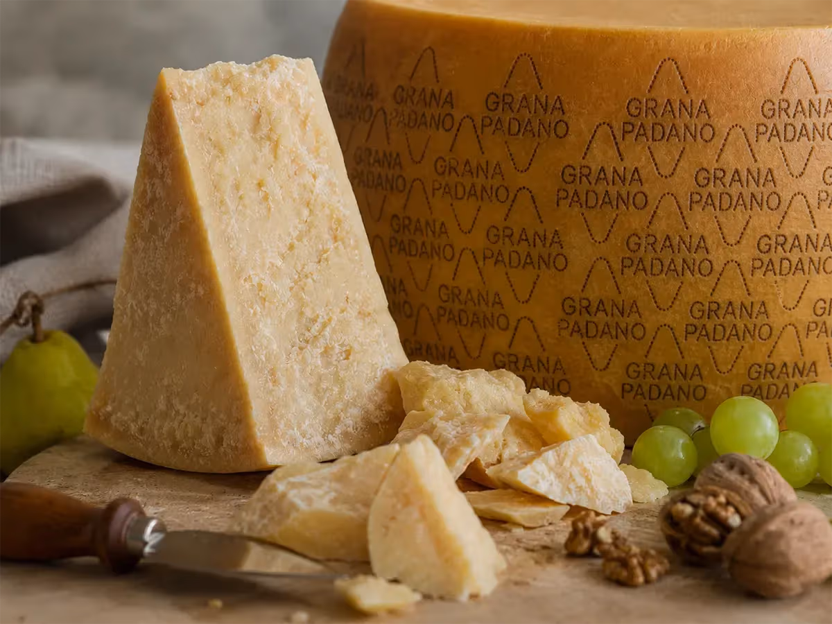 Spicchio triangolare di Grana Padano con uva verde noci e scaglie su tagliere