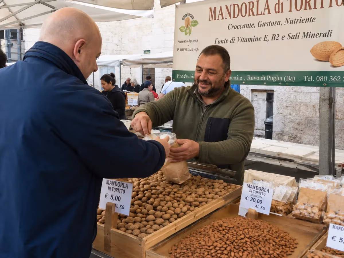 Venditore al mercato pugliese cede sacchetto di Mandorla di Toritto a cliente sorridente