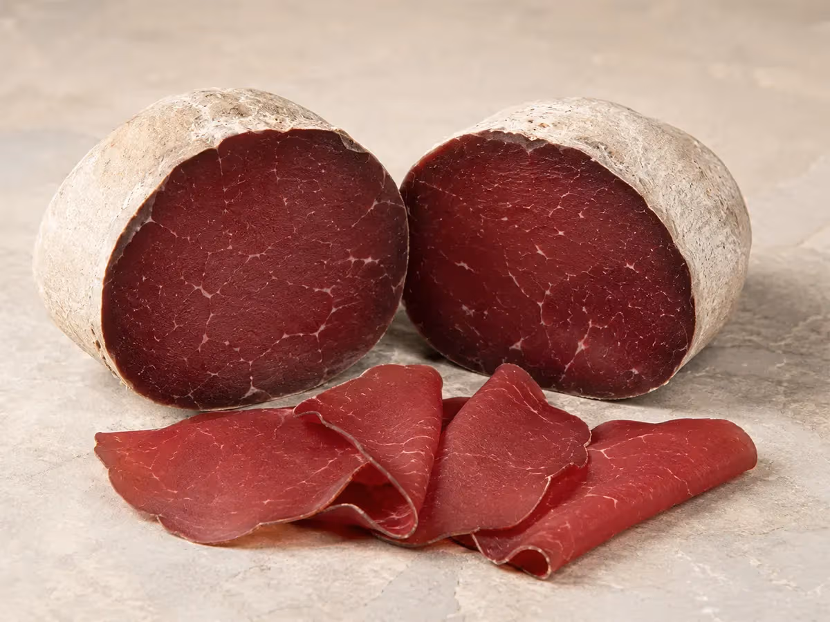 Due metà di bresaola della Valtellina tagliate mostrano sezione trasversale rossa con venature bianche