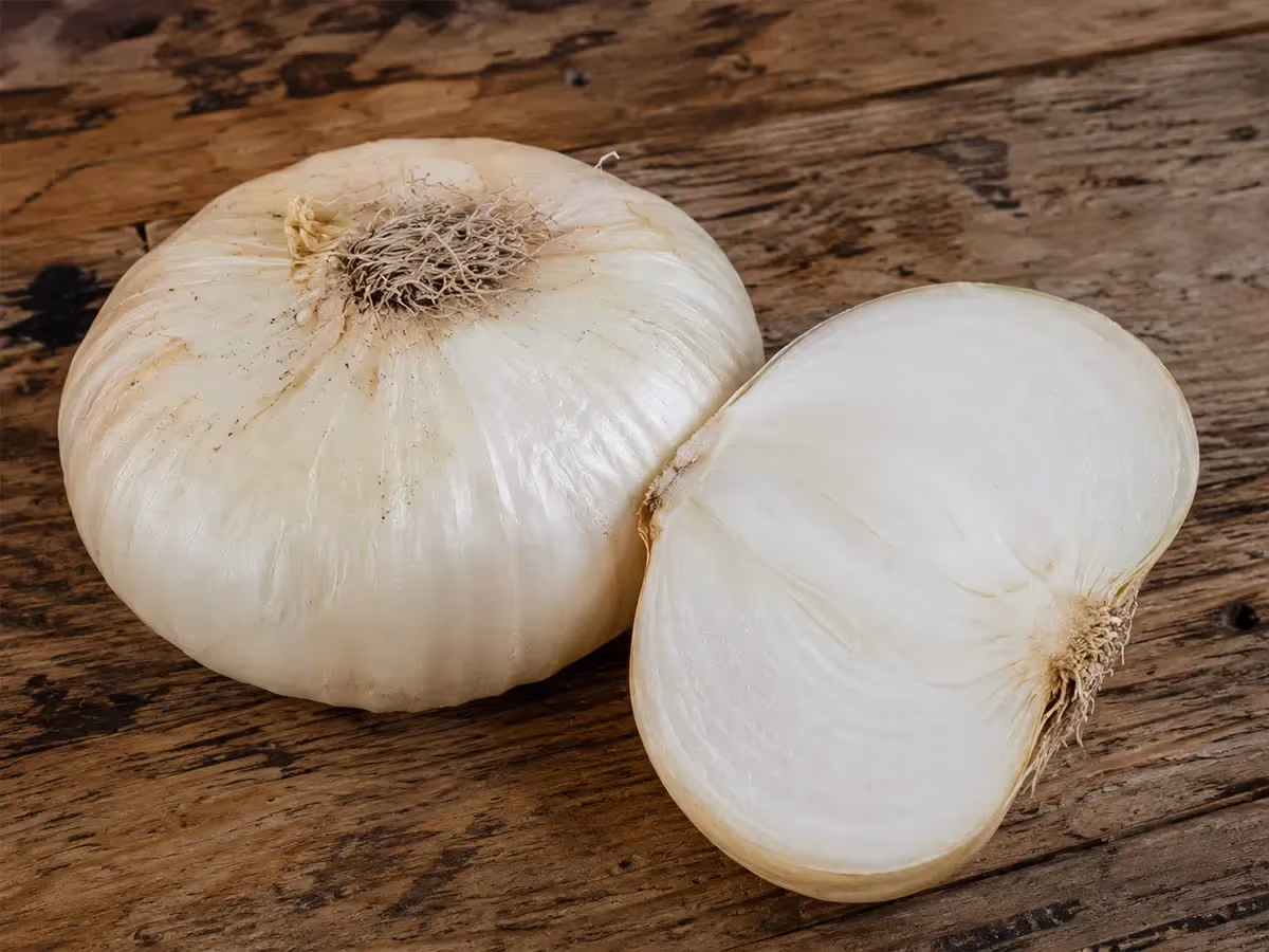 Cipolla di Giarratana intera e mezza tagliata su superficie in legno rustico