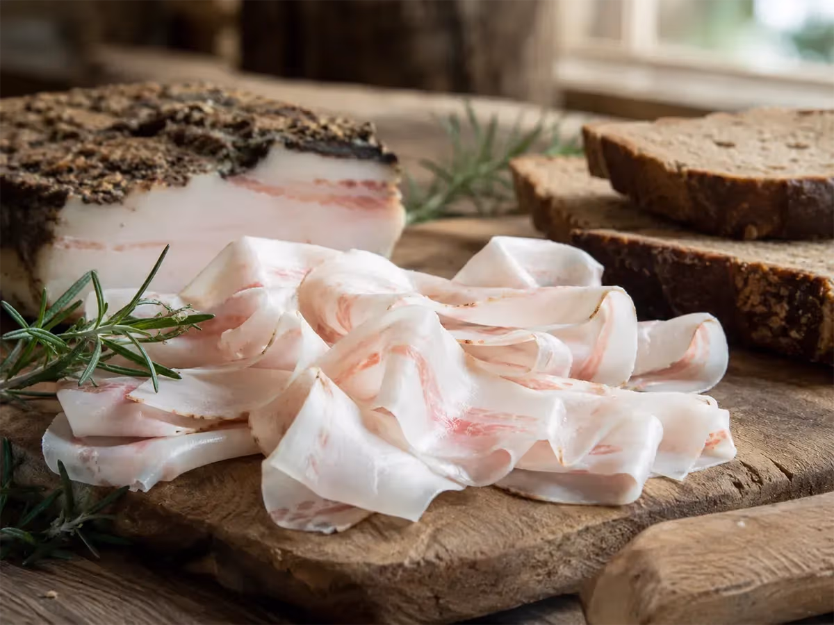 Lardo di Arnad DOP a fette sottili con rametto di rosmarino fresco e pane di segale scuro