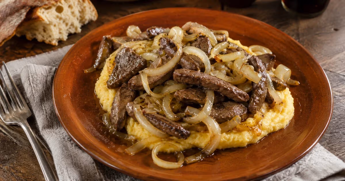 Fegato alla veneziana con cipolle appassite su polenta cremosa in piatto di terracotta